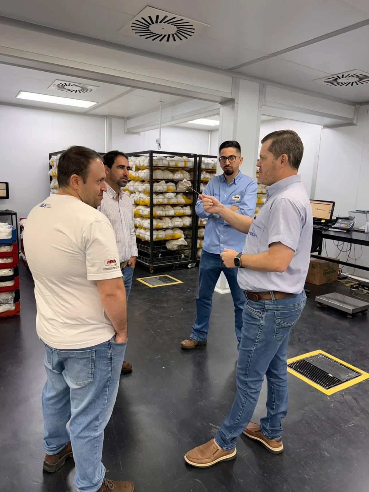 Participantes conversam no laboratório, entre prateleiras de amostras