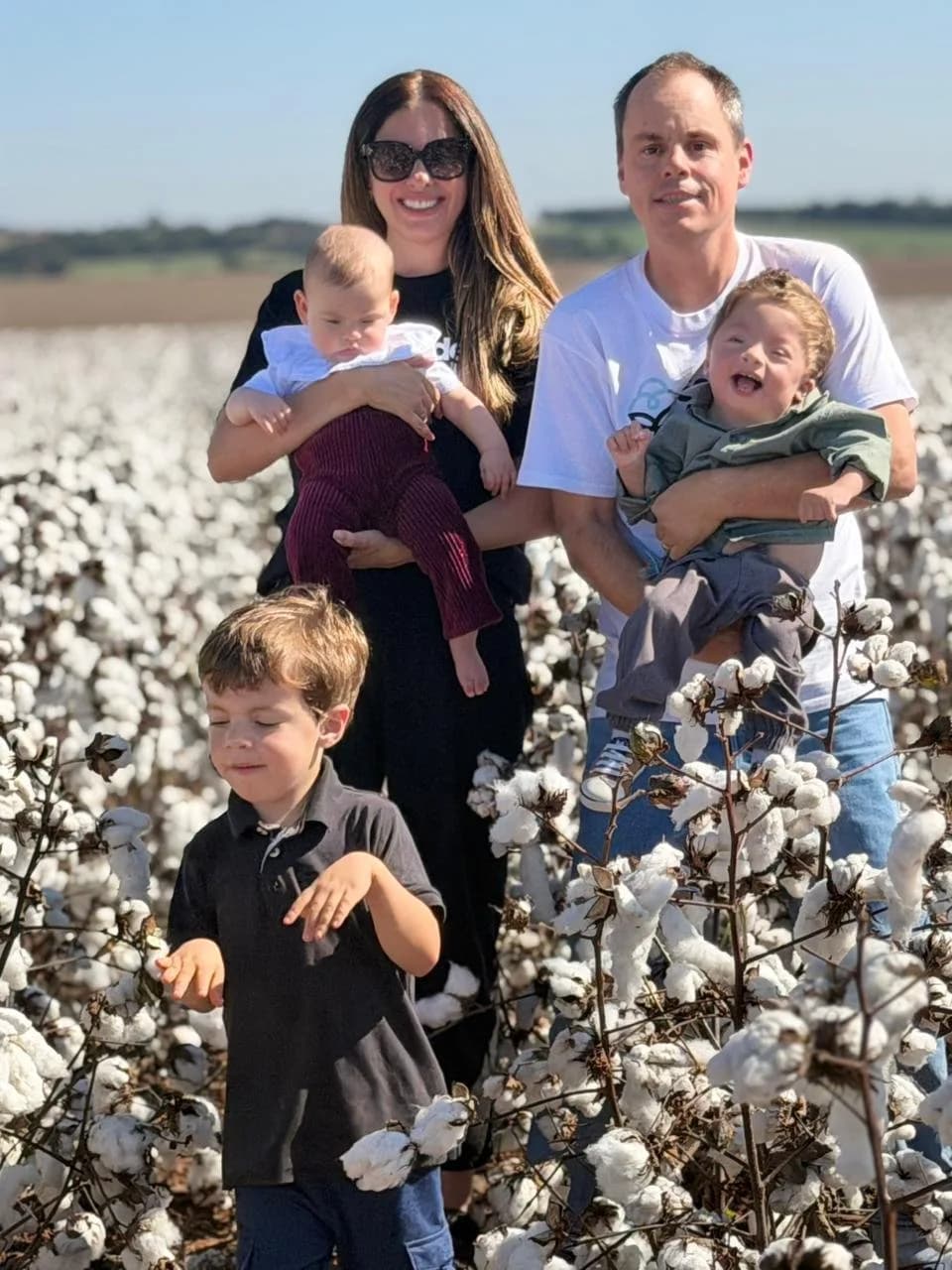 Casal com três crianças em pé no meio de um algodoal