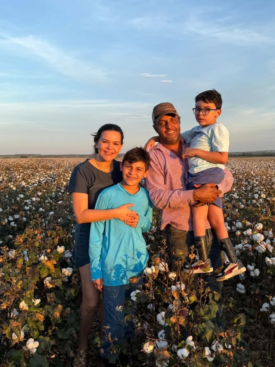 Família de quatro pessoas em um algodoal, no fim da tarde