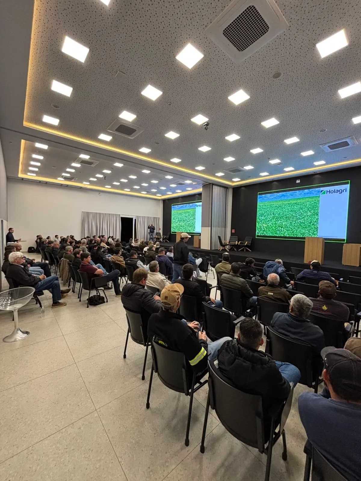 Plateia acompanha a apresentação, com o telão à frente
