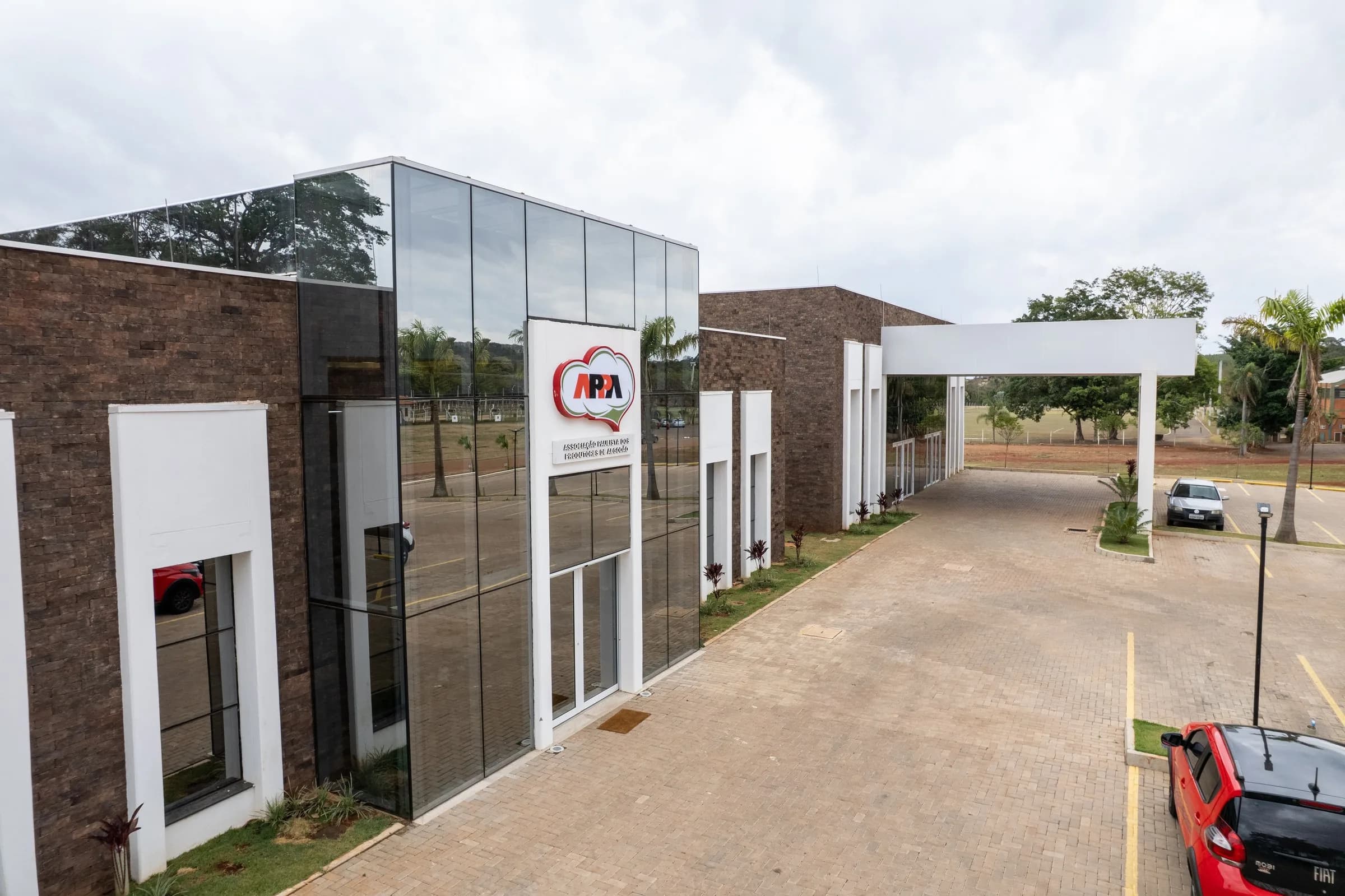 Fachada da sede em ângulo, com o volume de tijolo e o de vidro